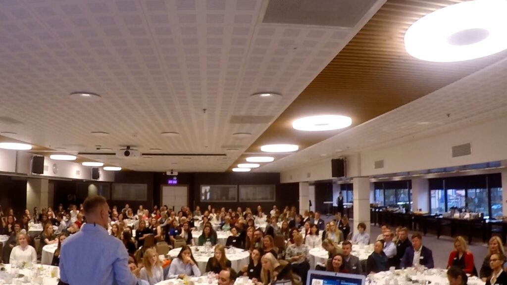John K. Bates speaking to a large corporate audience
