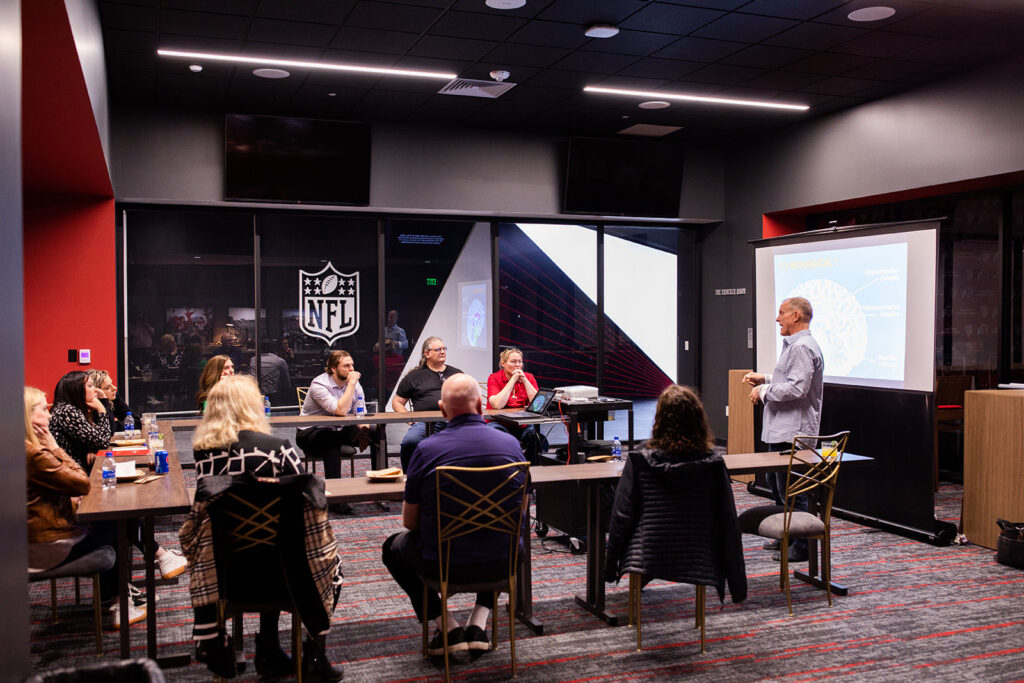 John Bates facilitating an executive leadership communication workshop with participants seated around the room