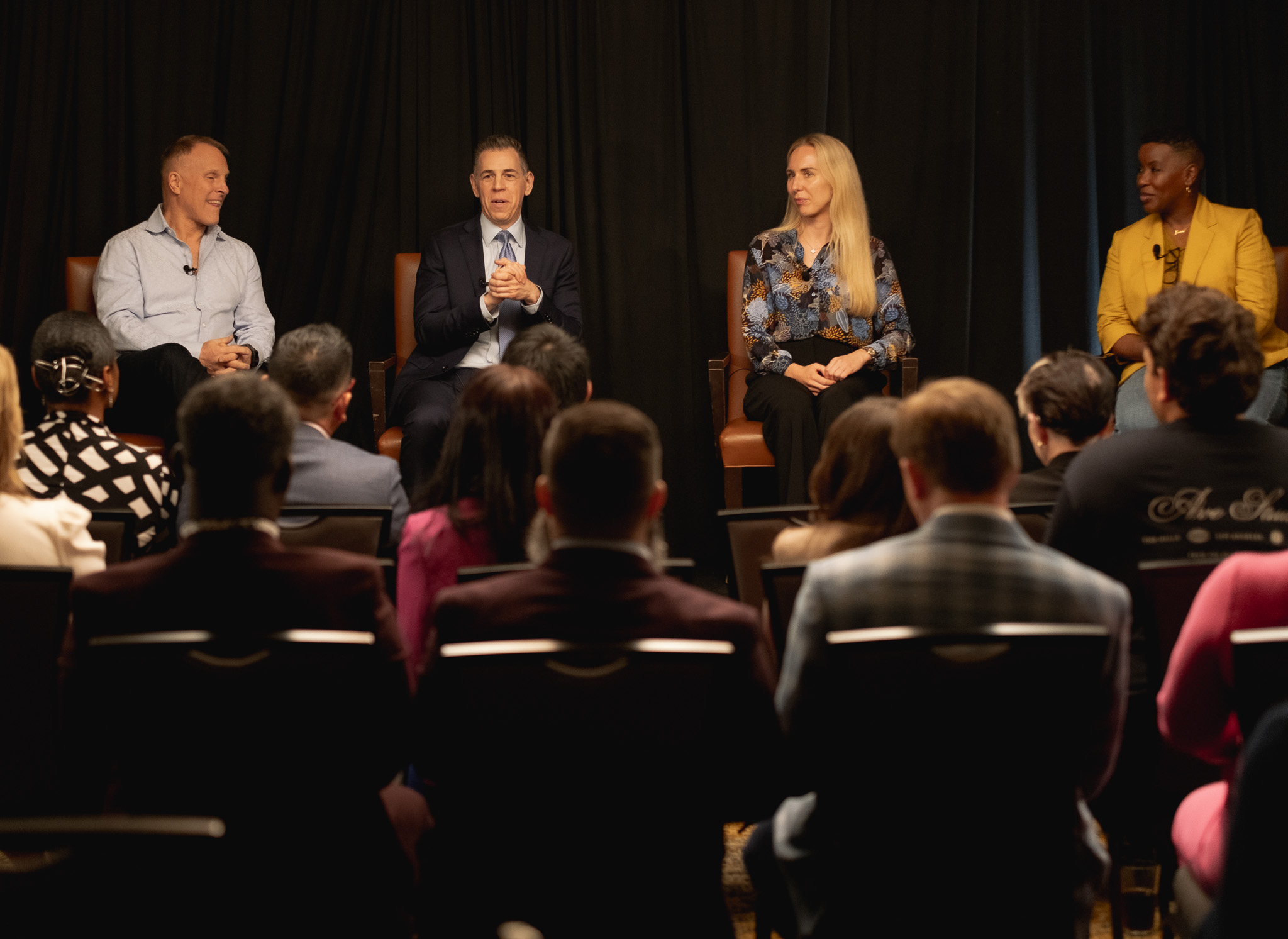 John K. Bates speaking with fellow executives on a panel before a live audience