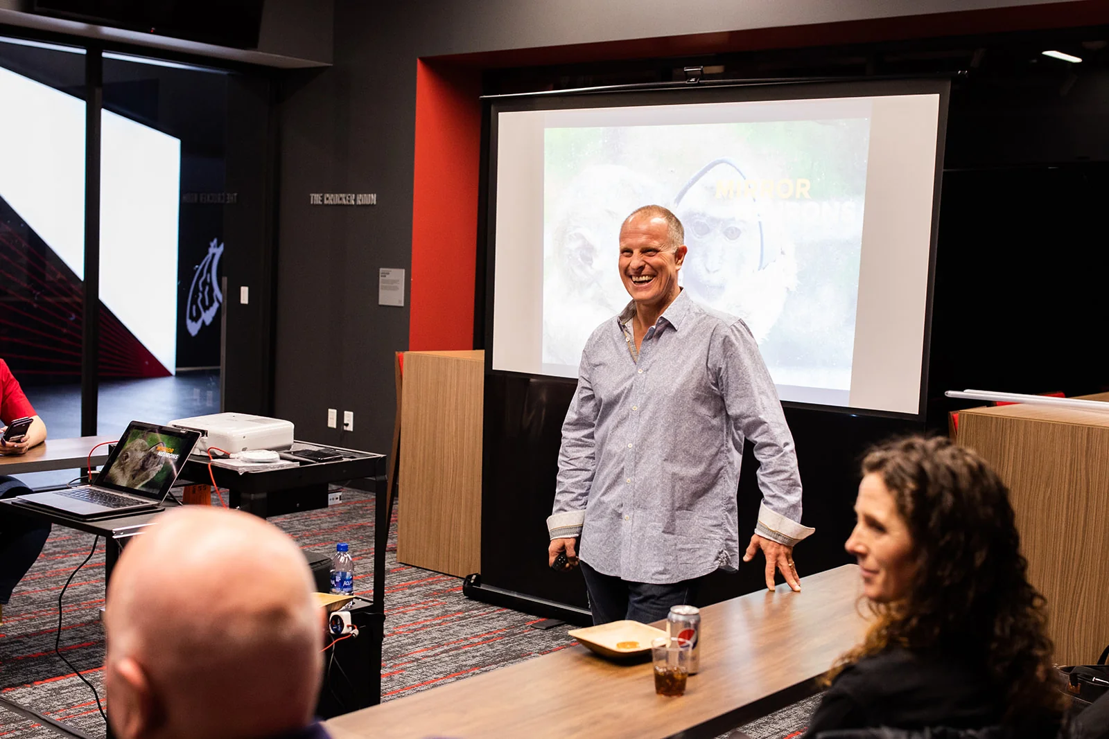 John K. Bates leading a communication workshop with participants seated around a conference table.